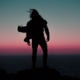 Silhouette eines Menschen mit wehenden Haaren auf einem Felsvorsprung über dem Meer bei Sonnenuntergang – Sinnbild für das Erreichen der Spitze