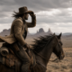 Ein Cowboy zu Pferd hält sich schützend die Hand an den Hut und blickt in eine weite, karge Wüstenlandschaft mit Felsformationen – Sinnbild für die Suche nach Führungskräften